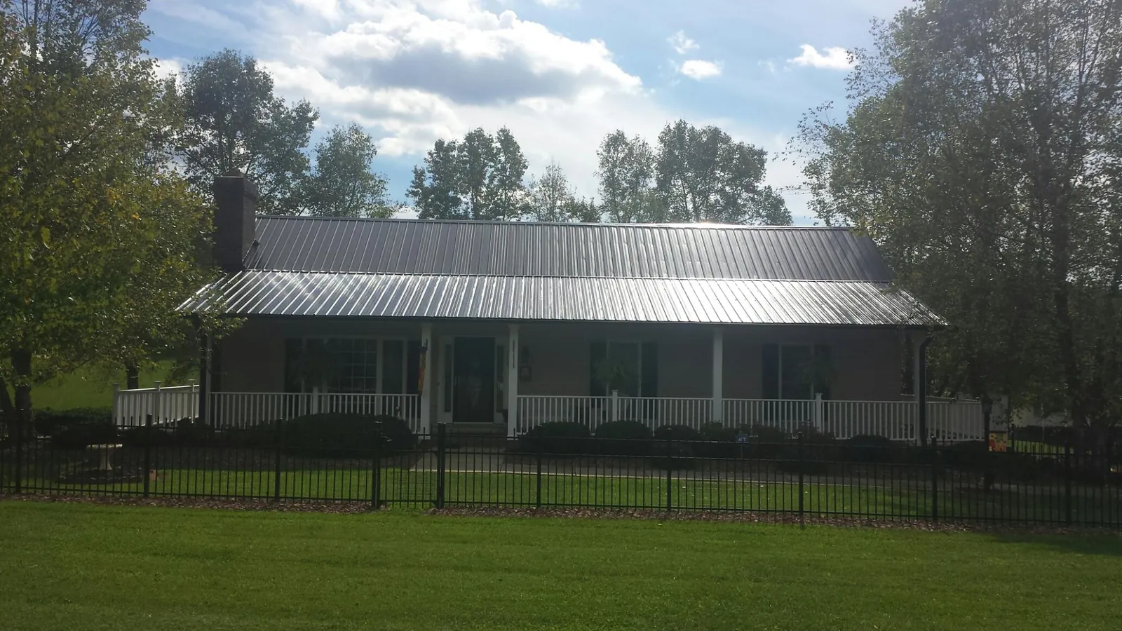 Gray metal roof on a brick ranch with a full width front porch — Gutter Guard Installation work by our crew in Geneseo
