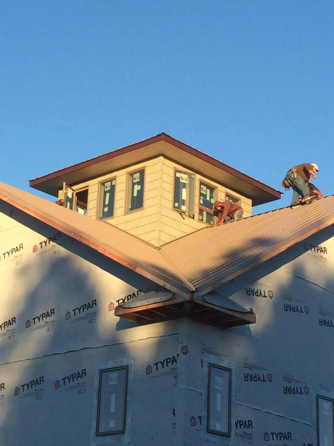 Roofers working around a rooftop cupola on a new metal roof at sunset — Roof Waterproofing in Geneseo by Roofing Brothers
